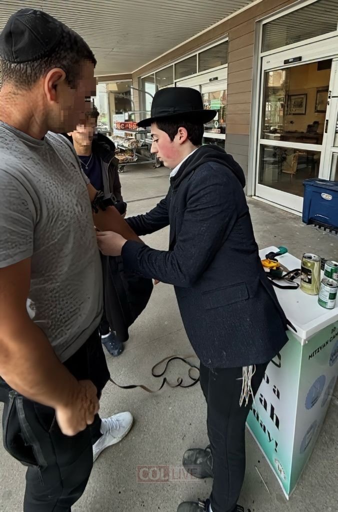 Mendy helping a man put on tefillin at a Mitzvah Campaign stand